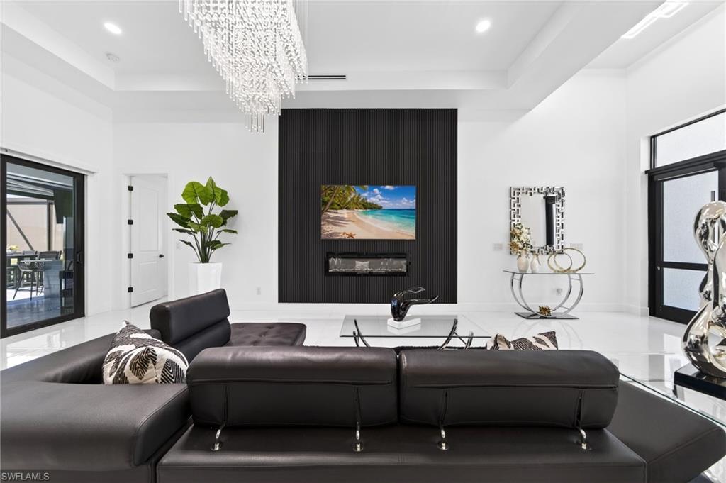 Spacious living area featuring high ceilings, a contemporary linear chandelier, polished tile flooring, and a striking black accent wall