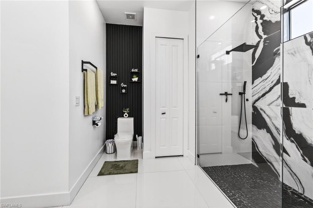 Contemporary bathroom featuring a spacious glass-enclosed shower with black and white patterned wall tile, a rainfall showerhead, and a handheld spray
