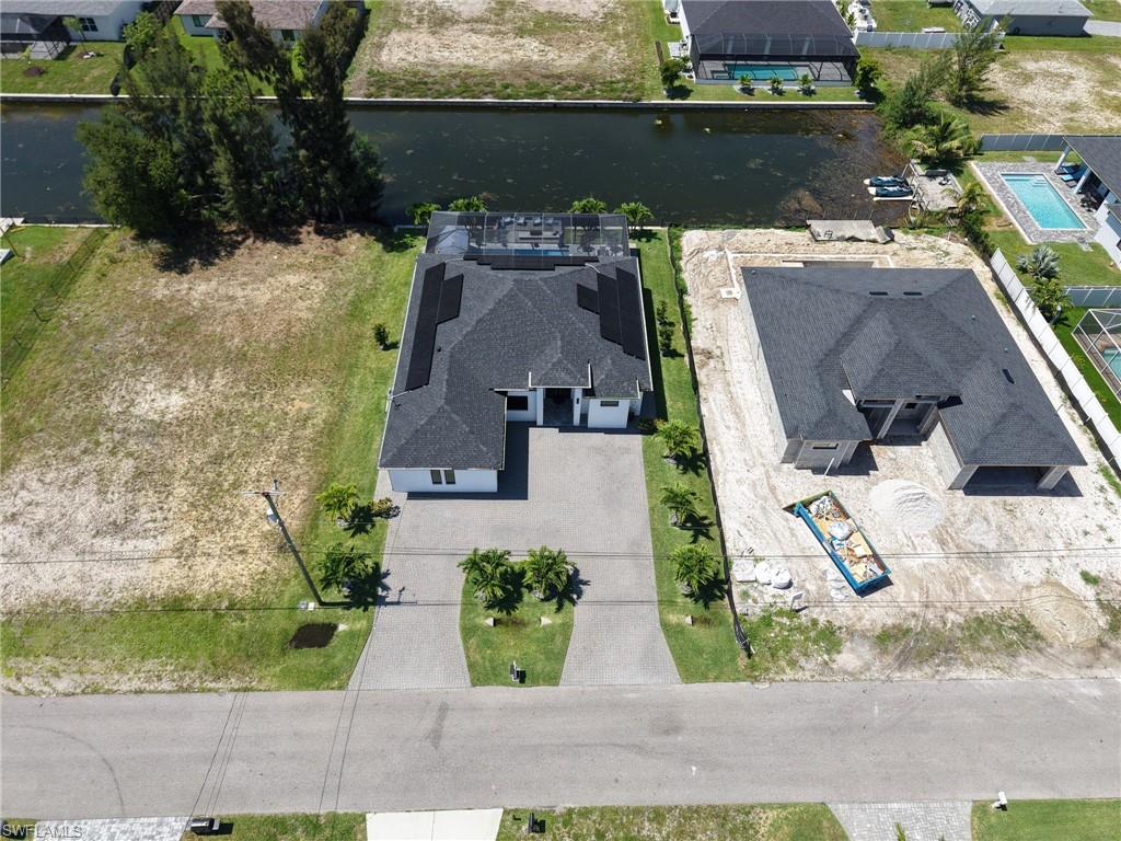 Newly constructed residence featuring a gray shingle roof, solar panels, and a screened-in pool area