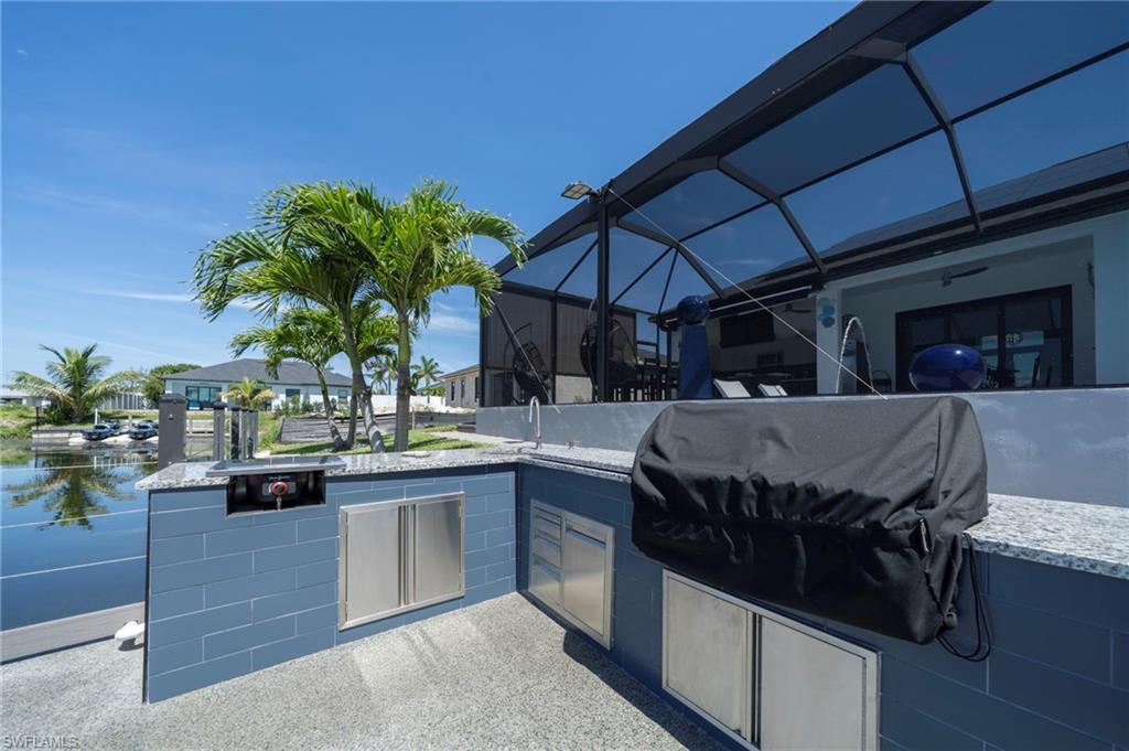Outdoor kitchen featuring a built-in grill, stainless steel cabinetry, and a light-toned countertop