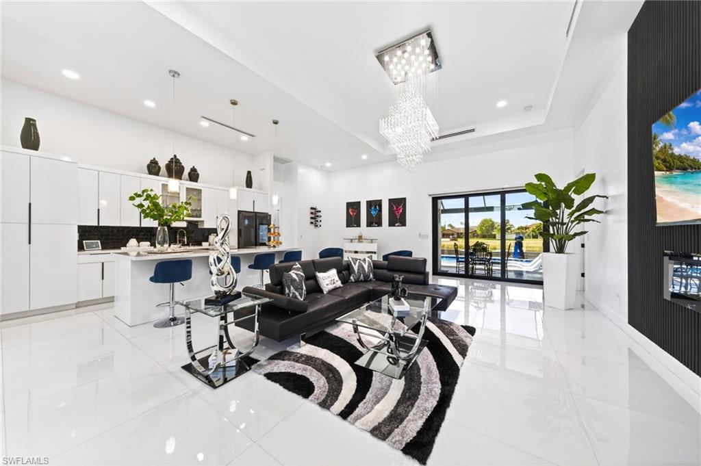 Open-concept living space with sleek white tile flooring and a multi-tiered crystal chandelier