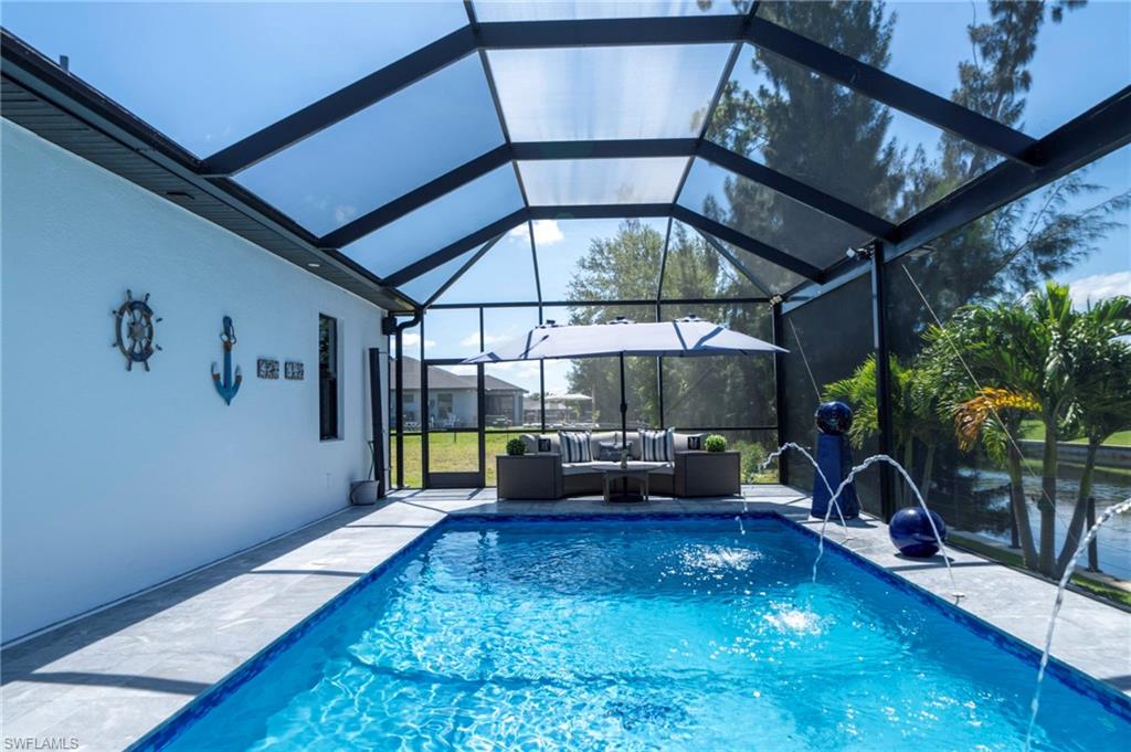 Screened lanai featuring a swimming pool with water features, a paver deck, and lush landscaping