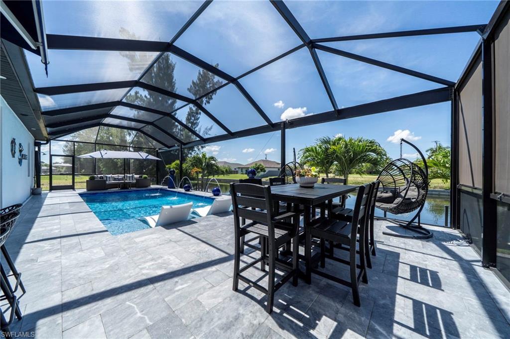 Screened lanai featuring a swimming pool, stone-finish patio, and waterside frontage