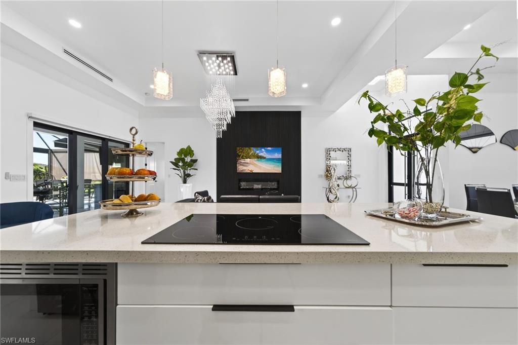 Kitchen island featuring a built-in induction cooktop, integrated microwave, and light-toned countertop