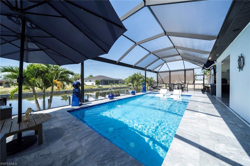Screened lanai featuring a swimming pool, expansive canal frontage, and grey tile flooring