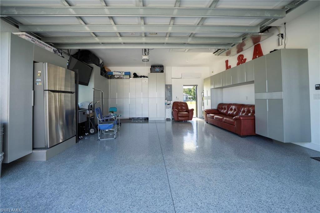 Spacious garage featuring a durable epoxy floor, extensive built-in cabinetry for organized storage, and a single exterior door providing direct outdoor access, and A/C