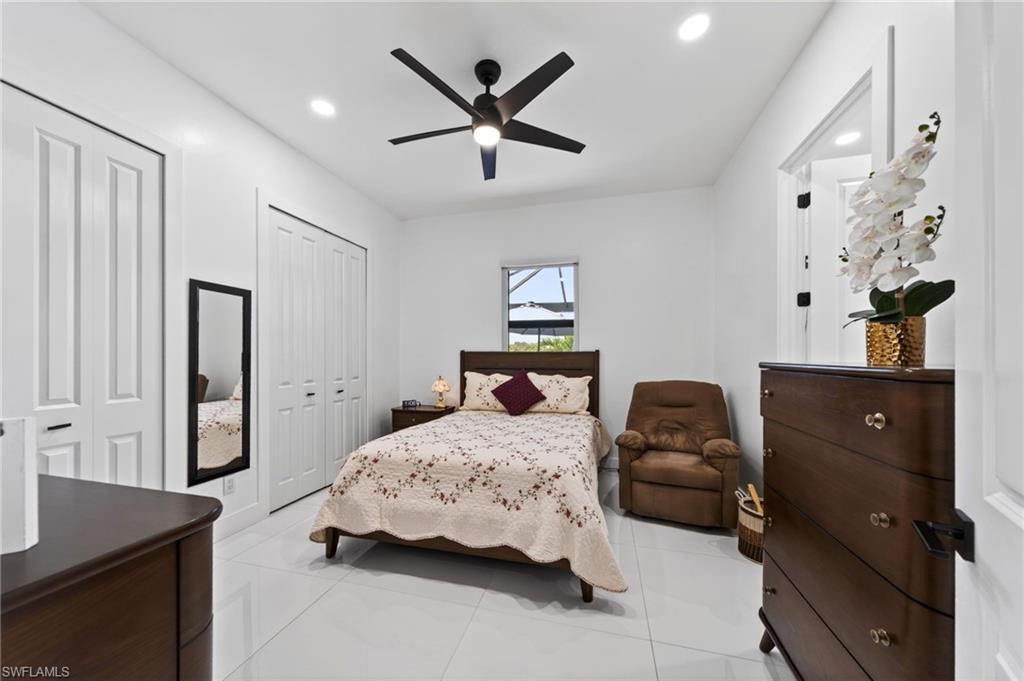 2nd bedroom, Bright interior featuring white walls and tile flooring, a dark wood-finish ceiling fan, recessed lighting, and white bi-fold closet doors and full bathroom