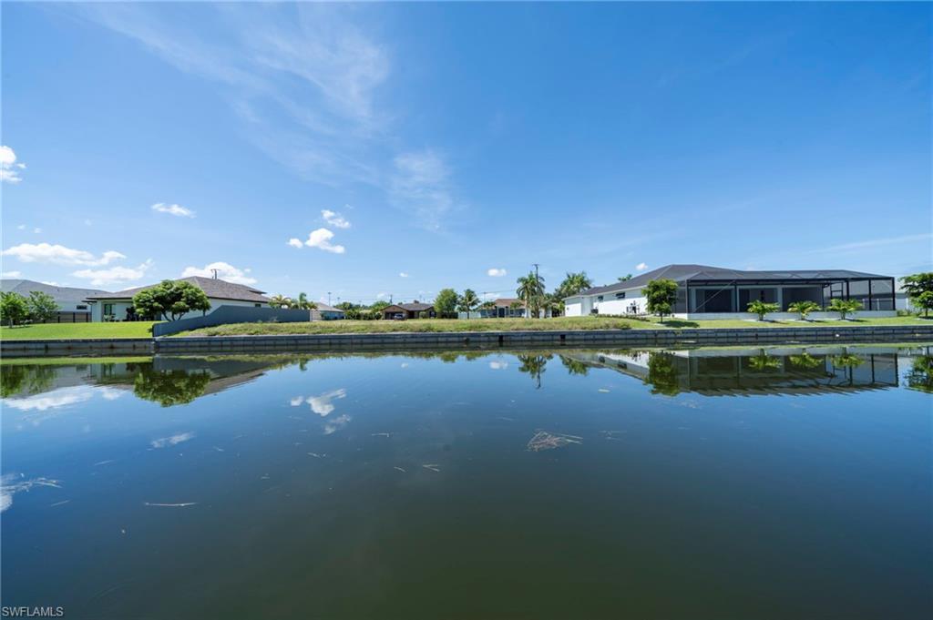 Waterfront property featuring a canal, private dock, screened-in lanai, and manicured landscaping