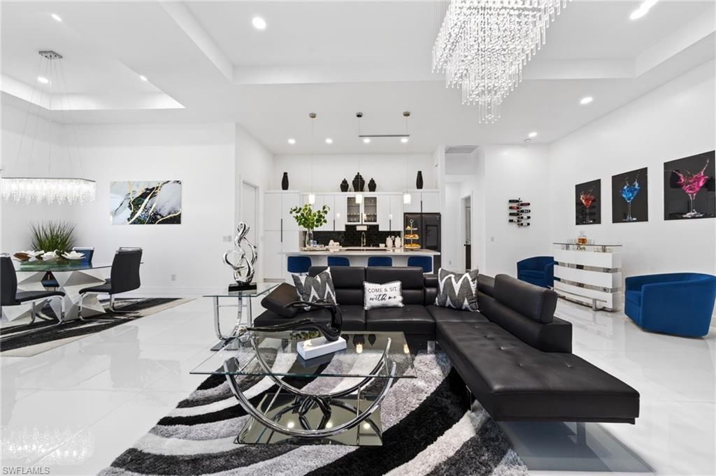 Open-concept living space featuring high ceilings with recessed lighting, bright white flooring, and a modern kitchen with a breakfast bar