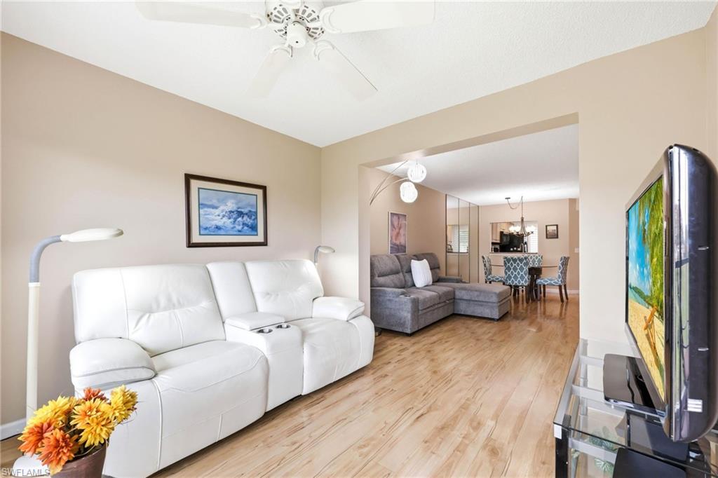 Living area featuring wood-finish flooring, a neutral color palette, and a ceiling fan with integrated lighting