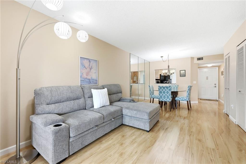 Living area featuring wood-finish flooring, neutral wall tones, and a mirrored accent wall