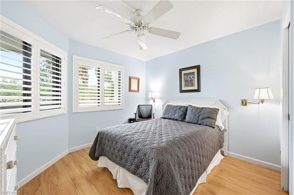 Bedroom featuring wood-finish flooring and two windows with white plantation shutters
