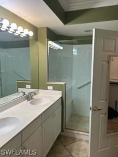 Dual vanity with integrated sinks and white cabinetry, complemented by a glass-enclosed shower, decorative wall molding, and tiled flooring
