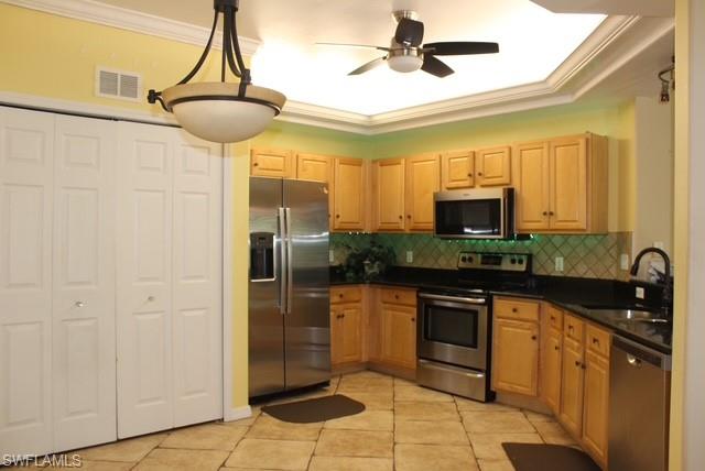 Kitchen featuring stone-look tile flooring and light wood cabinetry with dark countertops