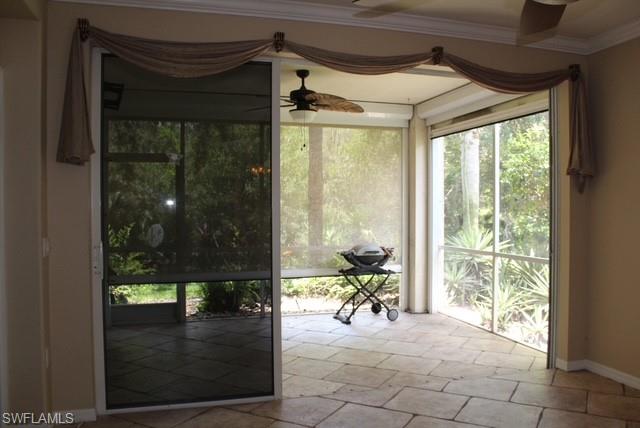 Screened patio featuring stone-look tile flooring, ceiling fans, and an outdoor screened enclosure