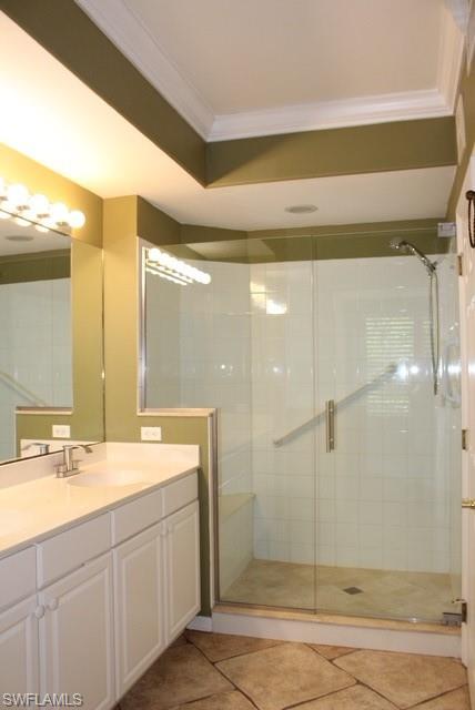 Bathroom featuring a frameless glass shower enclosure with a built-in bench, a single vanity with a white countertop and undermount sink, and stone tile flooring