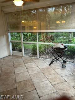 Screened patio featuring large format tile flooring and a ceiling fan with integrated lighting