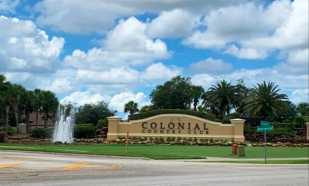 "Colonial Country Club" signage with architectural pillars, surrounded by landscaping featuring a fountain and palm trees