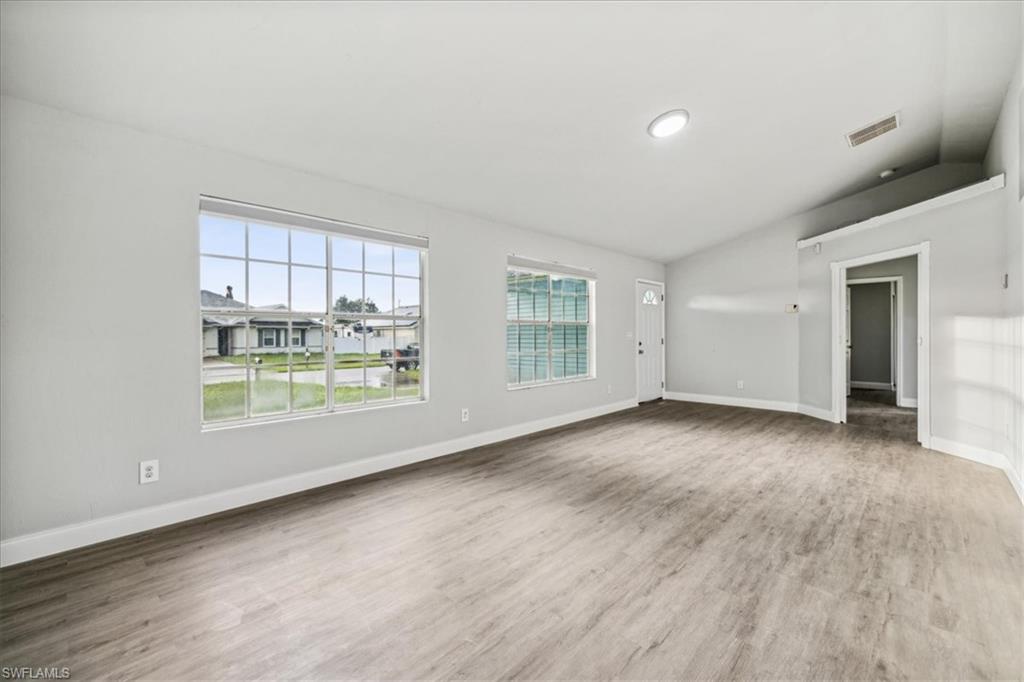 Unfurnished living room featuring vaulted ceiling and hardwood / wood-style floors