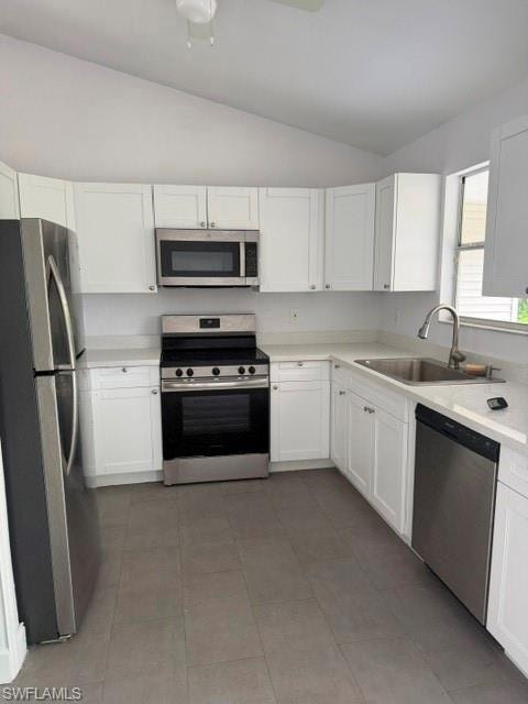 Kitchen featuring white cabinetry, stainless steel appliances, light countertops, and grey tile flooring