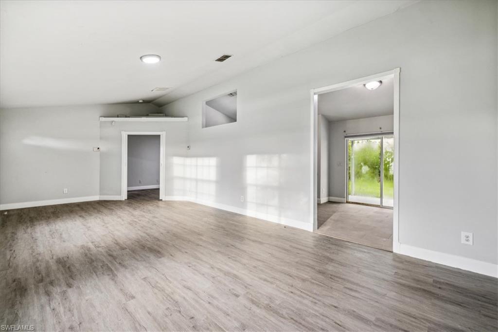 Empty room featuring wood-type flooring and vaulted ceiling