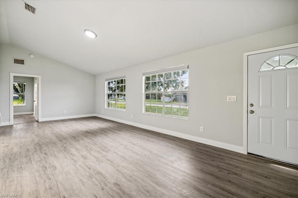Entrance foyer featuring dark hardwood / wood-style floors, vaulted ceiling, and a healthy amount of sunlight