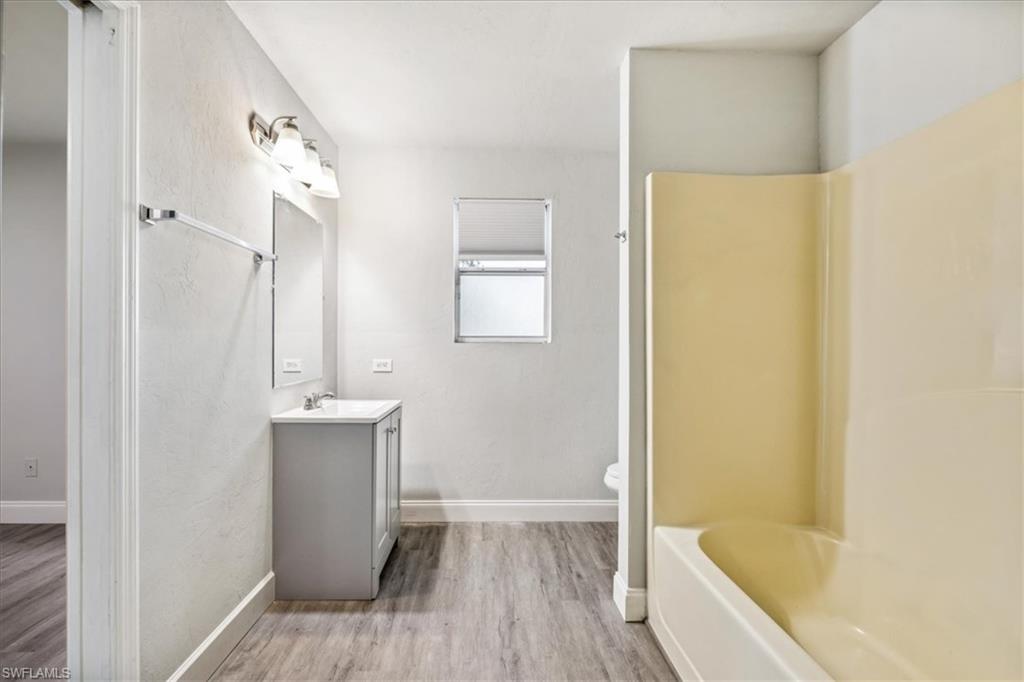 Full bathroom featuring vanity, separate shower and tub, toilet, and hardwood / wood-style flooring