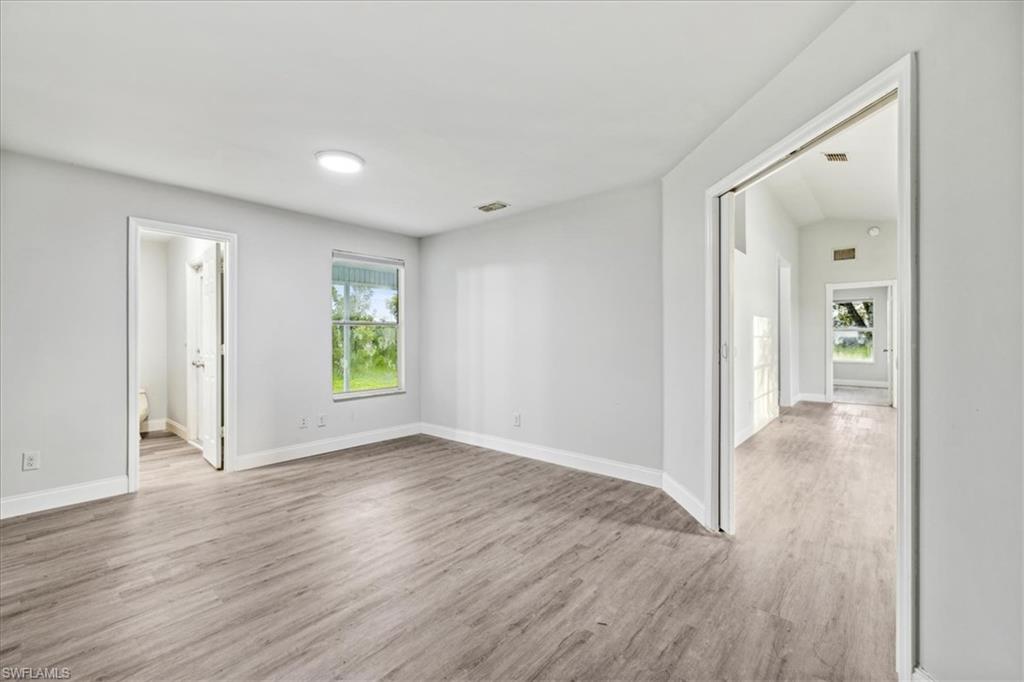 Spare room with light hardwood / wood-style flooring and lofted ceiling