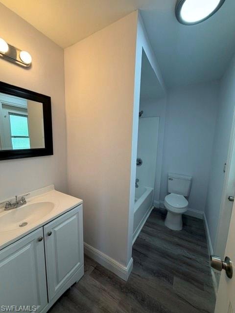 Bathroom featuring wood-finish flooring, a white vanity with a single basin sink, a framed mirror, and a full bathtub with a shower