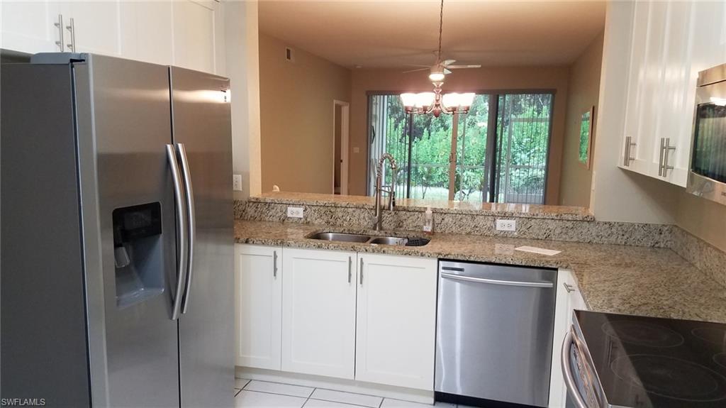 Kitchen featuring light stone countertops, stainless steel appliances, sink, decorative light fixtures, and white cabinets