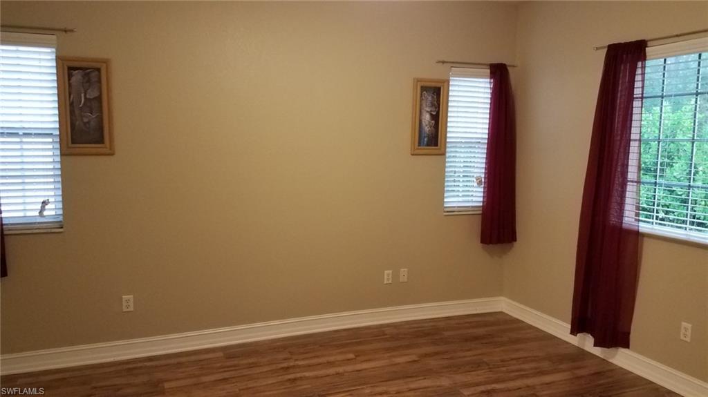 Empty room featuring plenty of natural light and dark hardwood / wood-style floors