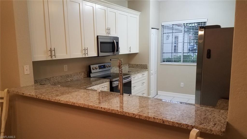 Kitchen featuring white cabinetry, light stone countertops, stainless steel appliances, kitchen peninsula, and light tile patterned flooring