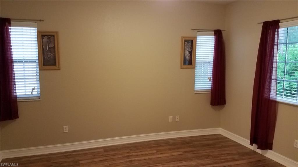 Spare room with a wealth of natural light and dark hardwood / wood-style flooring
