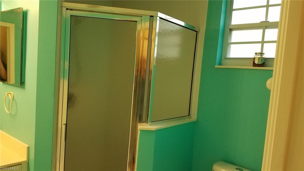 Bathroom with a shower with door, vanity, and toilet