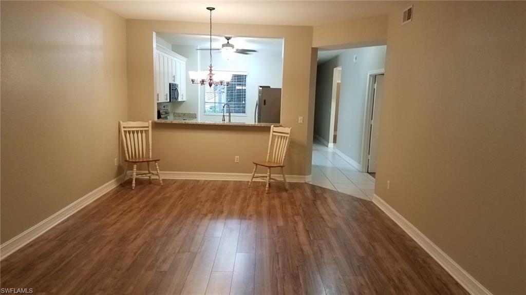 Empty room featuring sink, ceiling fan with notable chandelier, and hardwood / wood-style flooring