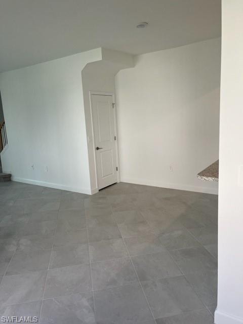 Empty room featuring baseboards and stairway