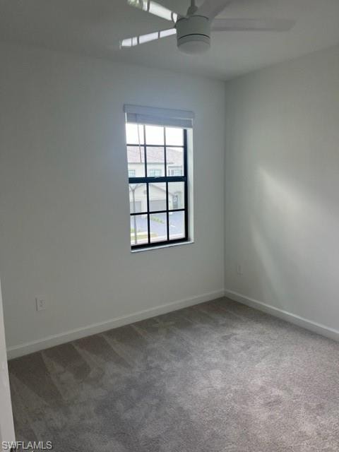 Carpeted empty room featuring a ceiling fan and baseboards