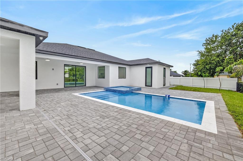 Expansive paver patio with a rectangular swimming pool and integrated spa