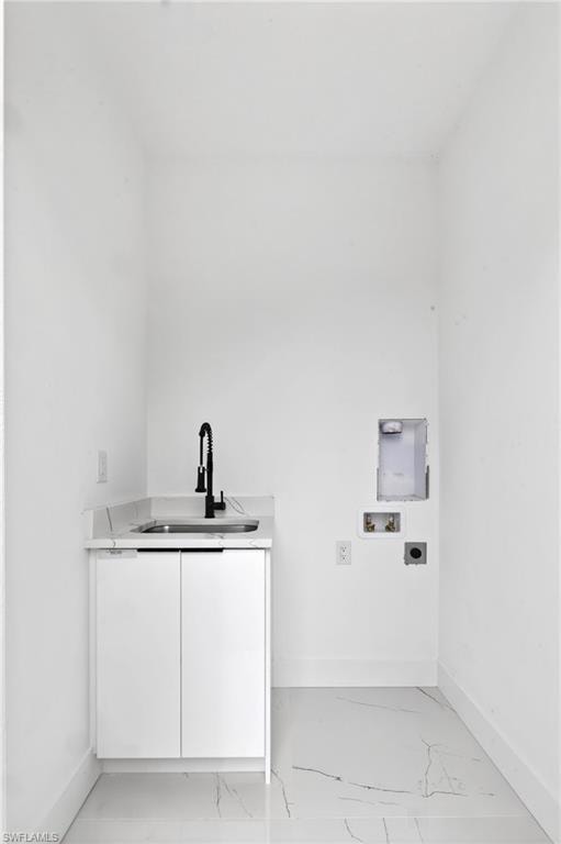 Utility room featuring a white single-basin sink with a matte black faucet, white cabinetry, a quartz countertop, and white tile flooring with veining