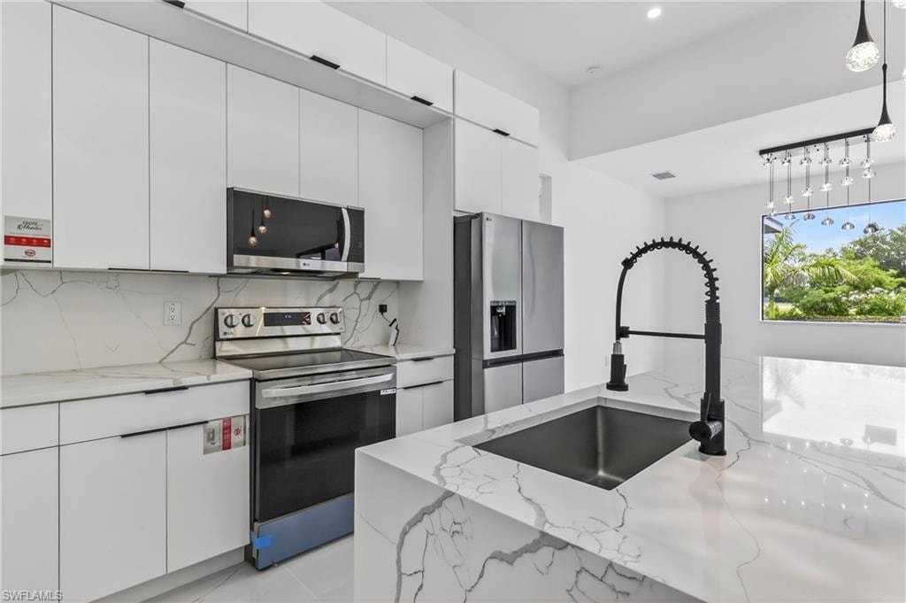 Modern kitchen featuring white flat-panel cabinetry and stainless steel appliances