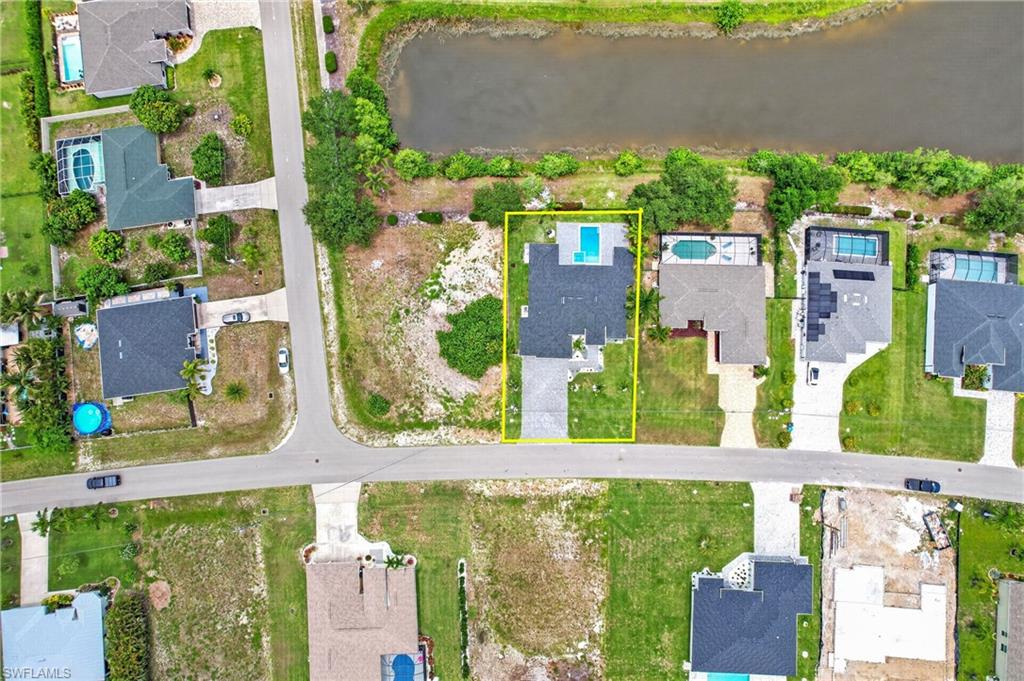 Aerial view showcasing a residential property with a dark shingle roof and a swimming pool