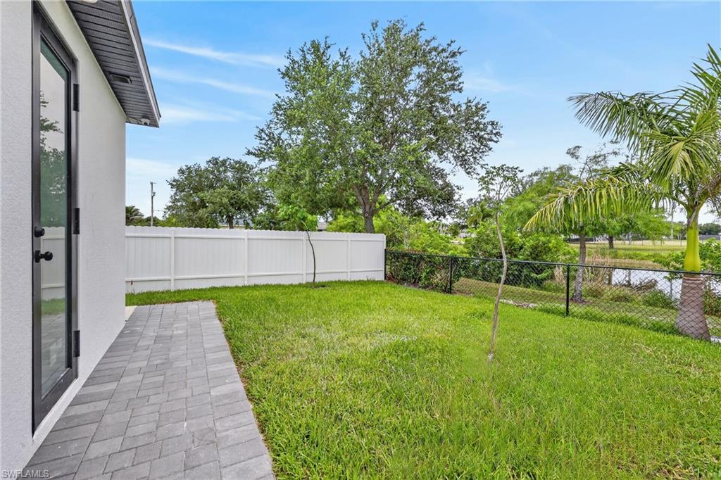 Expansive grass yard bordered by a white privacy fence and a black chain-link fence