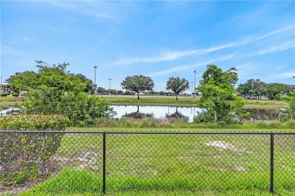 Expansive backyard area featuring a chain link fence, lush green grass, and mature landscaping