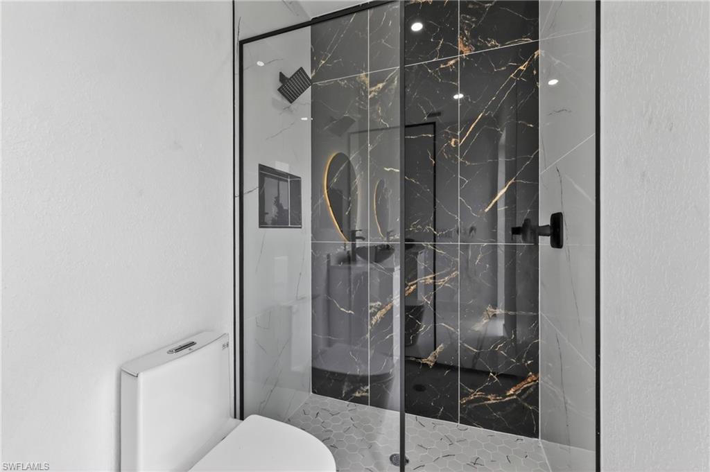 Contemporary shower enclosure featuring black-framed glass and black marble-effect wall tiling with gold veining