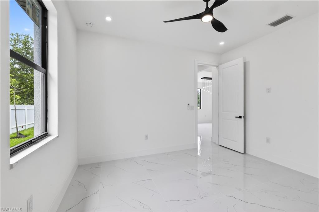 Spacious room featuring large format marble-look tile flooring, a modern black ceiling fan, recessed lighting, white walls, and a contemporary interior door with black hardware