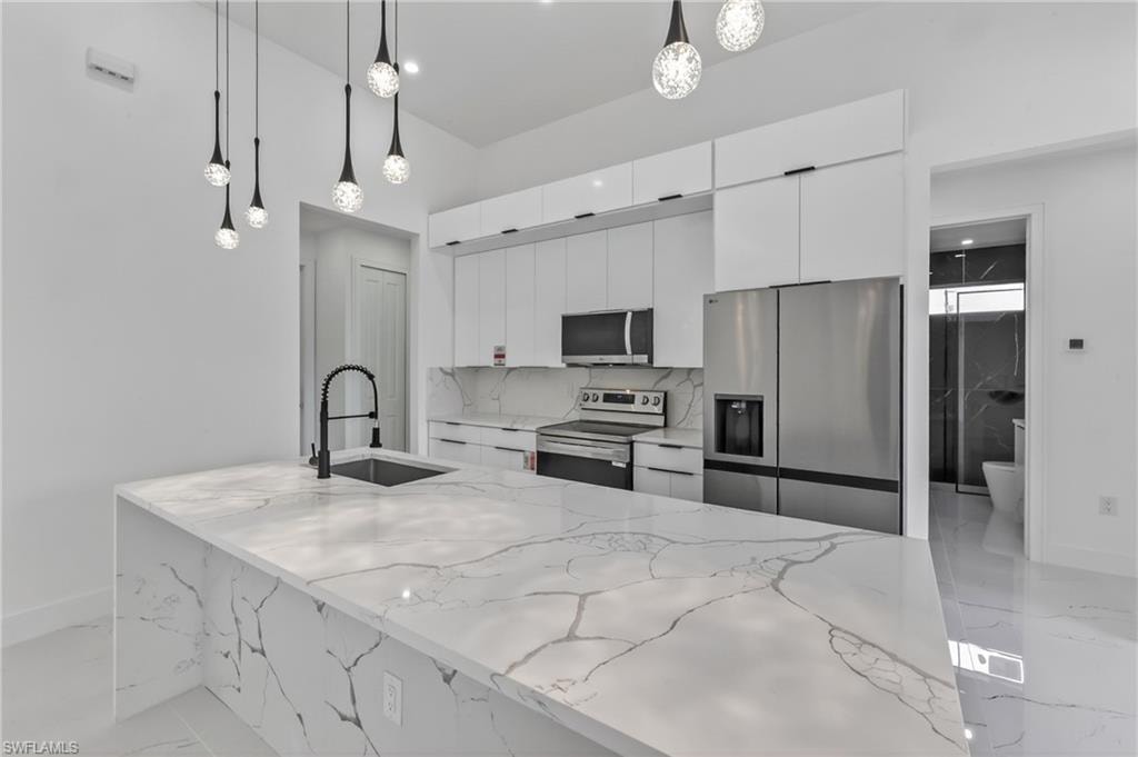 Spacious kitchen island featuring a waterfall-edge countertop and integrated sink with a matte black faucet