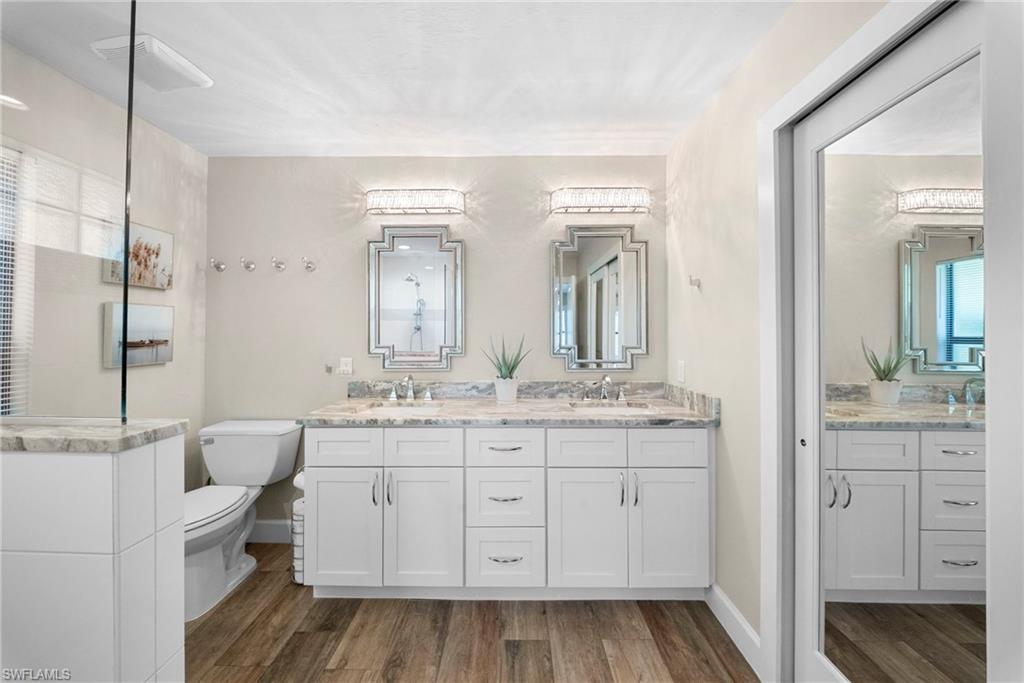 Dual vanity featuring white shaker cabinetry, stone countertops, and ornate framed mirrors