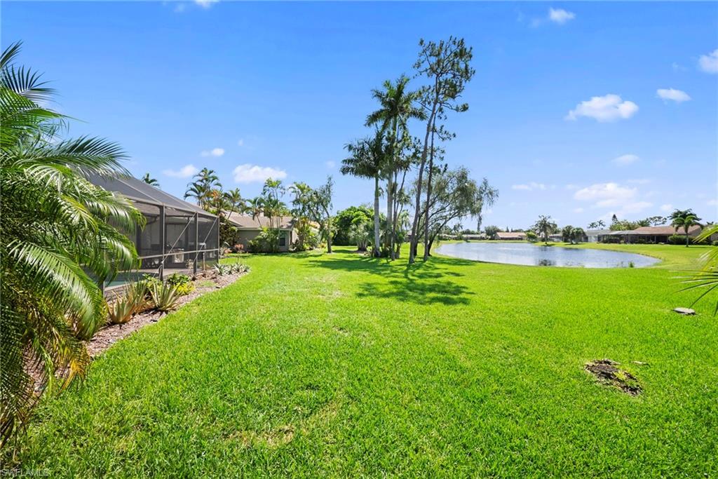 Expansive green lawn with a screened patio enclosure and established tropical landscaping