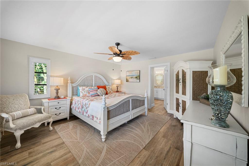 Light-filled room featuring wood-finish flooring, a ceiling fan with light fixture, and a window with plantation shutters
