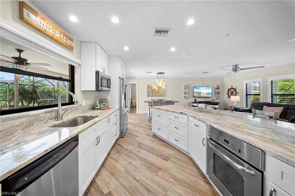 Expansive kitchen featuring white cabinetry, stainless steel appliances, and premium countertops